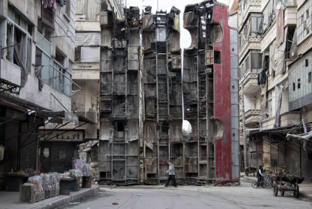 Em mar&ccedil;o de 2015, ao&nbsp;norte da cidade s&iacute;ria de Aleppo, um garoto passou por uma barricada improvisada, feita com restos de &ocirc;nibus. A barricada estava sendo usada para obstruir o campo de vis&atilde;o de snipers do regime de Assad e manter os civis em seguran&ccedil;a.