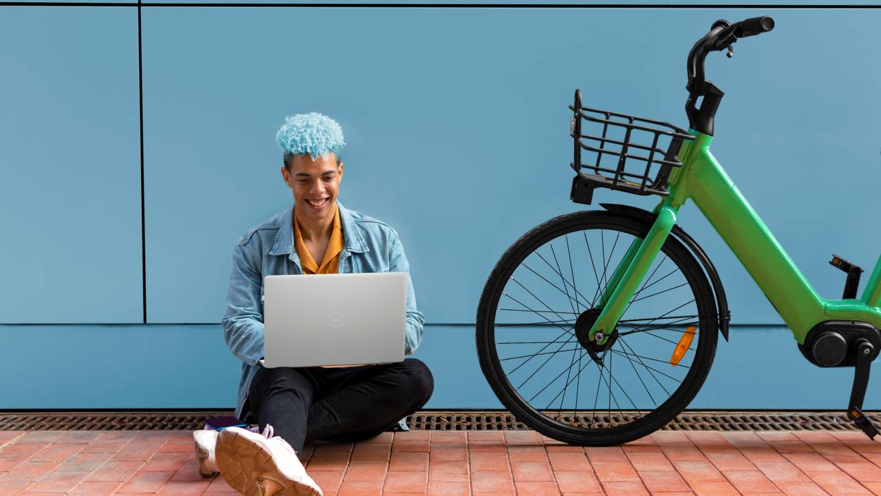 Homem sentado no chão, usando um Notebook Dell Inspiron 15 3000 Series.