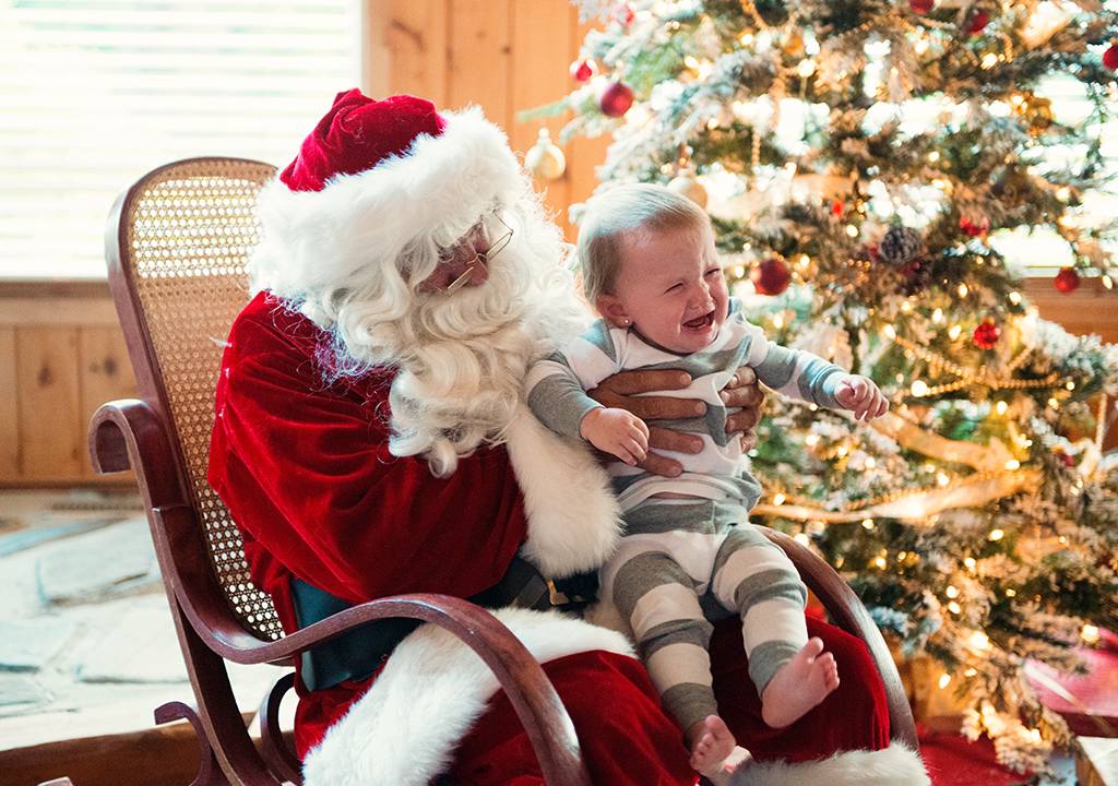 papai noel segurando uma criança chorando