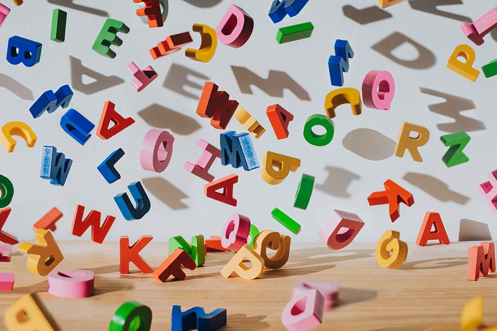 Fotografia de letras de madeira caindo em cima de uma mesa.