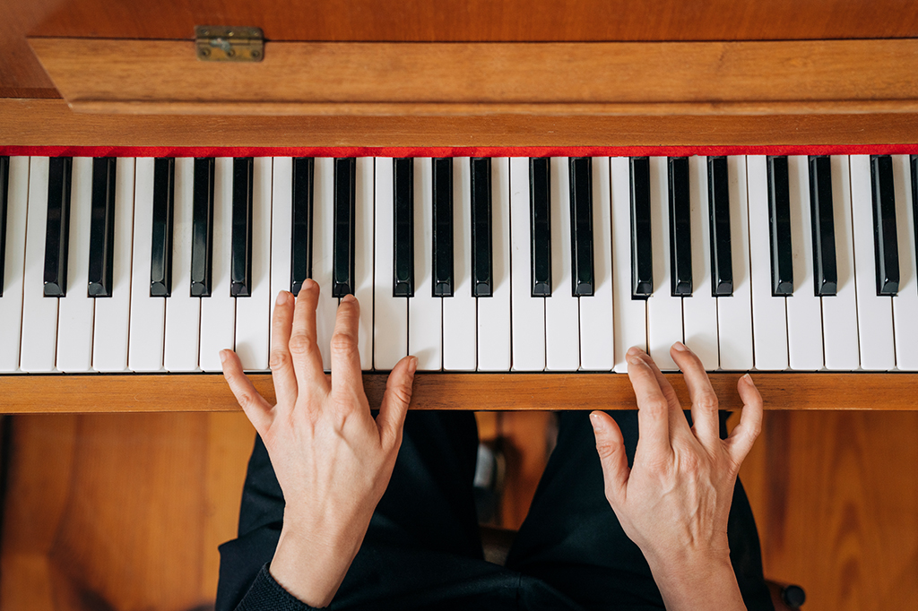 Mãos tocando teclas de piano vertical