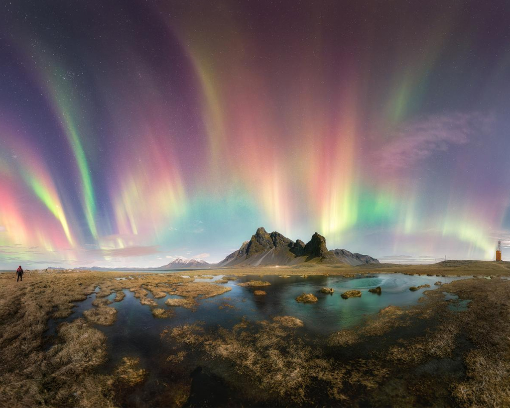 Aurora Boreal acima de montanha e lago.