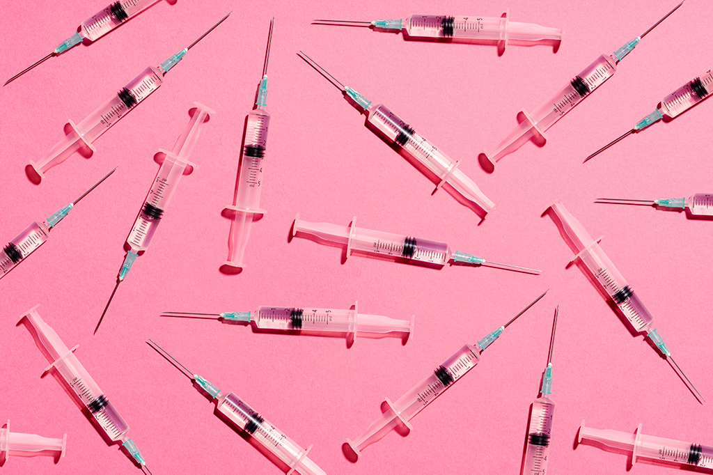 Diversas seringas dispostas arbitrariamente sobe um fundo de cor rosa.