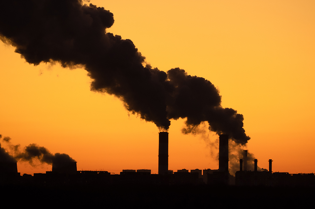 Chaminés expelindo gases para a atmosfera durante pôr-do-sol.