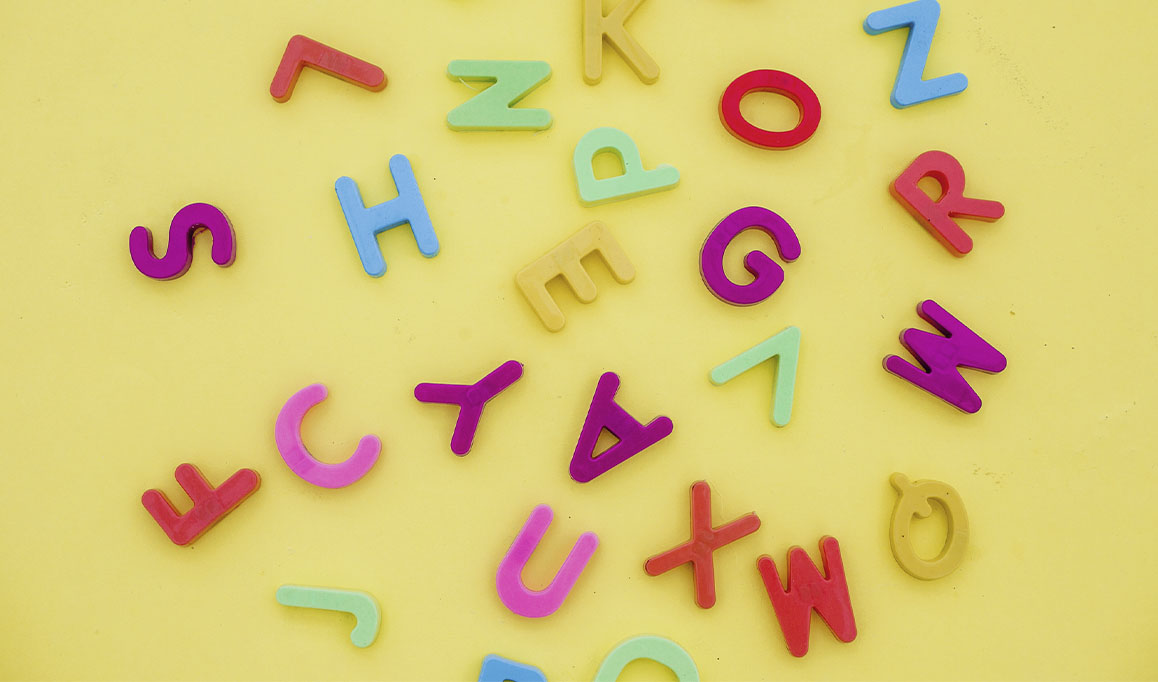 Foto de letras coloridas espalhadas em fundo amarelo.