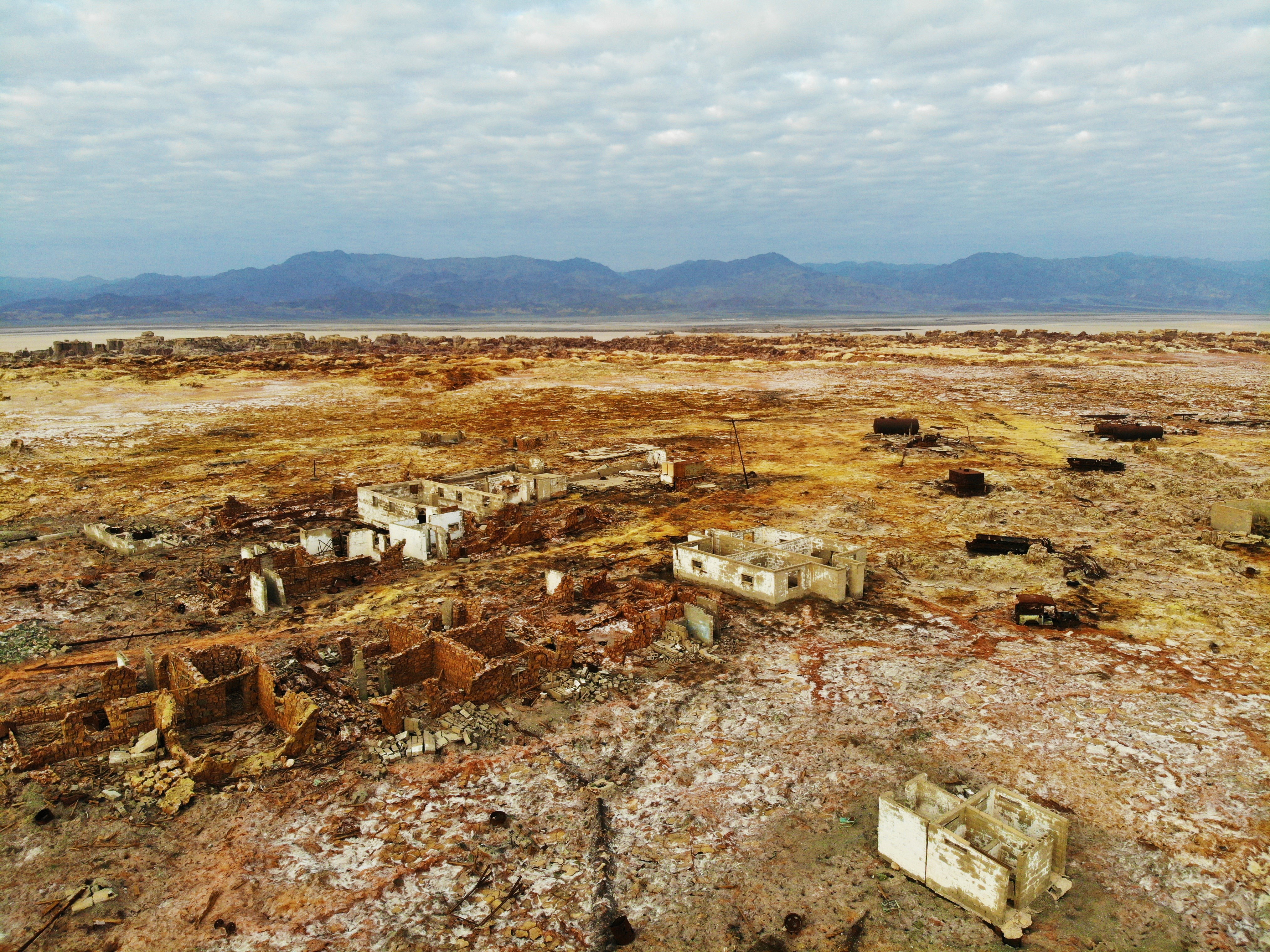 Algumas constru&ccedil;&otilde;es esparsas de um andar s&oacute;, destru&iacute;das e abandonados h&aacute; d&eacute;cadas, na paisagem desolada de um deserto et&iacute;ope, com solo amarelada. Ao fundo, uma cordilheira e c&eacute;u nublado.