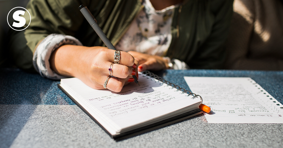Fotografia de uma menina escrevendo no caderno.