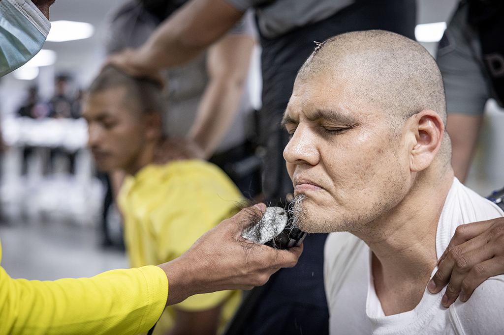 Fotografia de um guarda apara a barba de um detento rec&eacute;m-admitido supostamente ligado a organiza&ccedil;&otilde;es criminosas.
