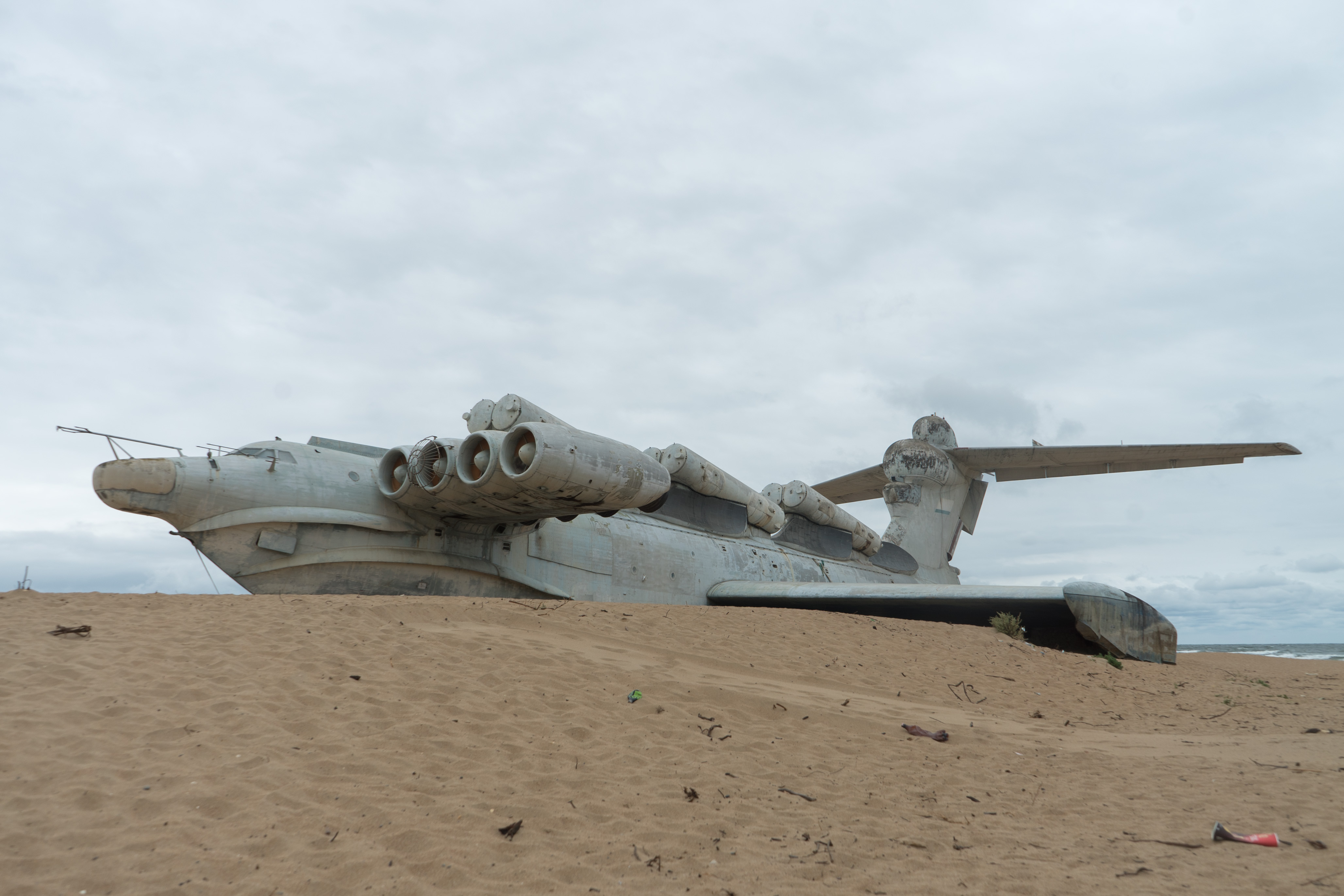 Ecranoplano sovi&eacute;tico abandonado na praia. &Eacute; um ve&iacute;culo cinza claro gigantesco com formato de avi&atilde;o e quatro turbinas instaladas de cada lado da fuselagem.
