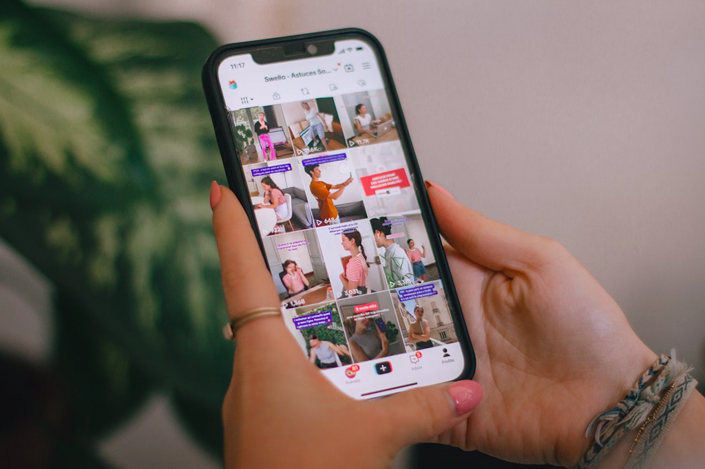 Fotografia de uma mão mexendo no tiktok pelo celular.