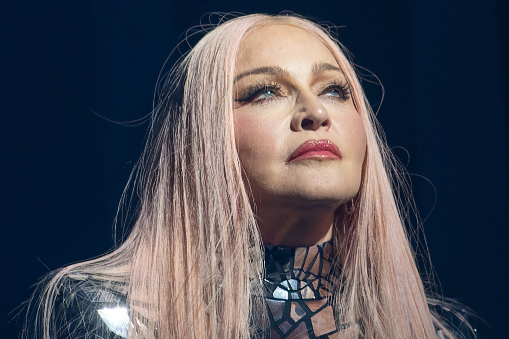 Imagem, em fundo preto, de uma mulher idosa, usando batom e cabelos loiros.