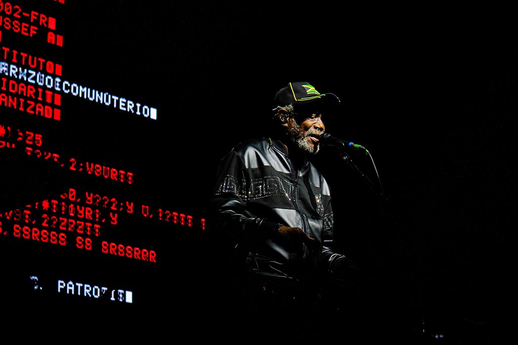 Fotografia do show do Massive Attack, Horace Andy cantando no palco.