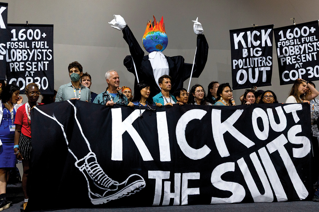 Imagem de pessoas reunidas segurando uma grande faixa e cartazes de protesto.