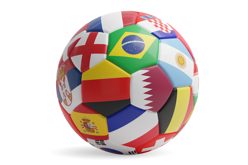 Imagem, em fundo branco, de uma bola de futebol com bandeiras de diversos países costuradas em gomos hexagonais e pentagonais.