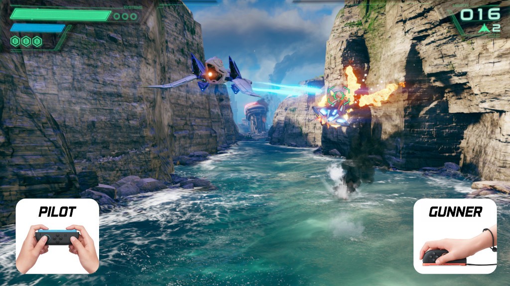 Cena de videogame com nave espacial azul atirando em inimigo laranja sobre um rio entre c&acirc;nions rochosos. No canto inferior esquerdo, m&atilde;os seguram um controle de videogame com a palavra 