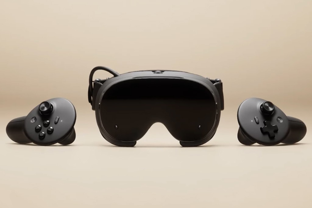 Um &oacute;culos de realidade virtual preto com lentes escuras e dois controles pretos, um de cada lado, sobre um fundo bege.